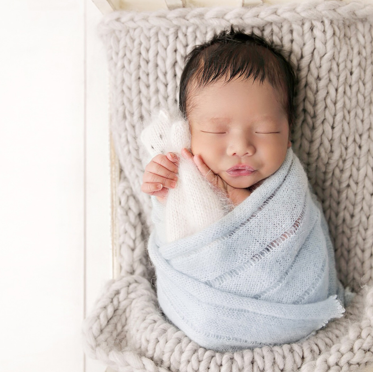 Sleeping newborn baby wrapped in soft blue fabric on a textured blanket during a Victoria BC photography session