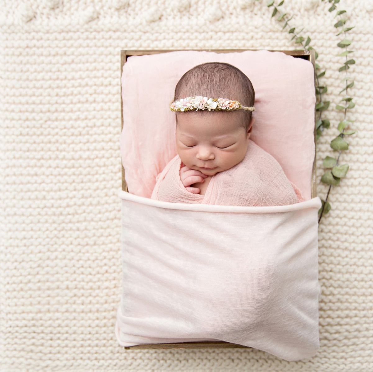 Sleeping newborn baby wrapped in soft fabric in a neutral styled photography setup in Victoria BC
